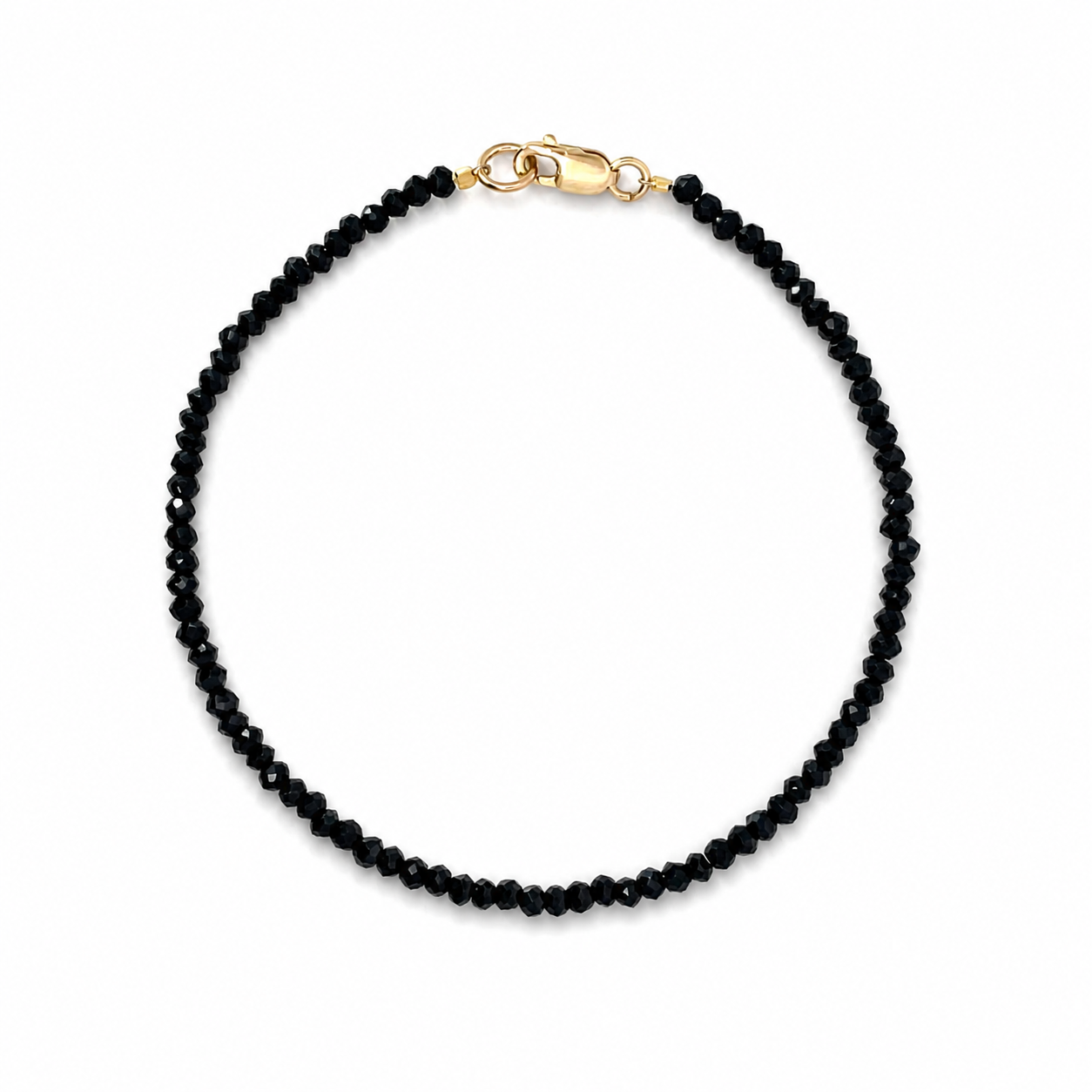 Black spinel bracelet with a 9K yellow gold clasp, featuring polished faceted gemstones and an elegant, timeless design.